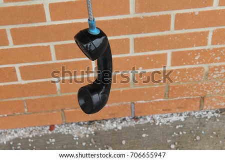 Old Bell Aliant payphone left off the Hook switch at a Barrie plaza with red brick background and loads of salt on the ground.    Royalty-Free Stock Photo #706655947