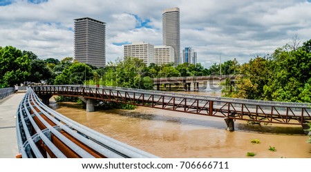 Panorama high and fast water rising in Bayou River from Rosemont pedestrian bridge with near town Houston in background, cloud blue sky. Heavy rains of Harvey Tropical Hurricane storm cause many flood