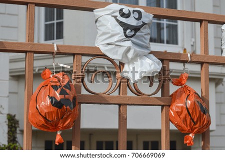 Artificial pumpkin heads from a plastic bag on the fence. Halloween