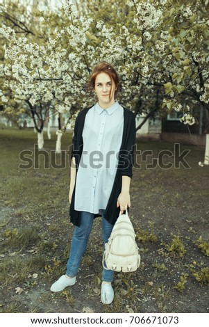 young, slender girl with long red hair walks in autumn Park.the student after the training sessions. posing in nature.style of clothing: street clothes.Wallpapers for your desktop. emotional portrait