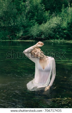 young slim girl posing in cold water. a warm summer day in Park street. hair in a bun, clean skin. clothing style: transparent blouse. Wallpaper for desktop