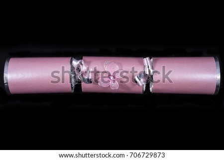 A studio shot of a Cracker or otherwise known as a Bon Bon. A cracker consists of a cardboard tube wrapped in a decorated twist of paper with a gift in the central chamber.