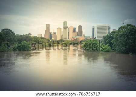 High and fast water rising in Bayou River along Allen Parkway and Memorial Drive with downtown Houston in background, storm cloud sky. Heavy rain from tropical storm caused many flood. Vintage tone