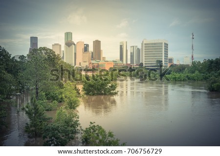High and fast water rising in Bayou River along Allen Parkway and Memorial Drive with downtown Houston in background, storm cloud sky. Heavy rain from tropical storm caused many flood. Vintage tone