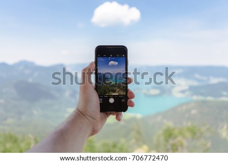 Concept of being a non stop line. Woman's hand holding smartphone with a blank screen on a background of mountains.