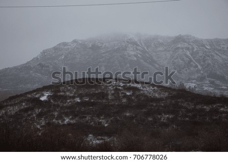 Mountains covered with snow. View of the mountains from a slope covered with grass. Mountains and forests on the sky background