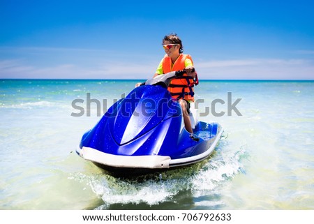 Teen age boy skiing on water scooter. Young man on personal watercraft in tropical sea. Active summer vacation for school child. Sport and ocean activity on beach holiday.