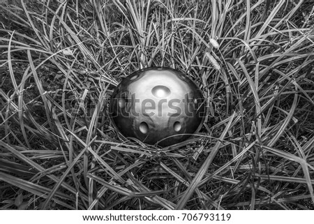 Hypnotizing black and white image of hang drum musical instrument in the grass. Meditation music background