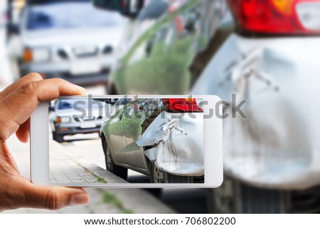 Car insurance agents take pictures of accident-damaged vehicles with a smartphone as a proof of insurance claim