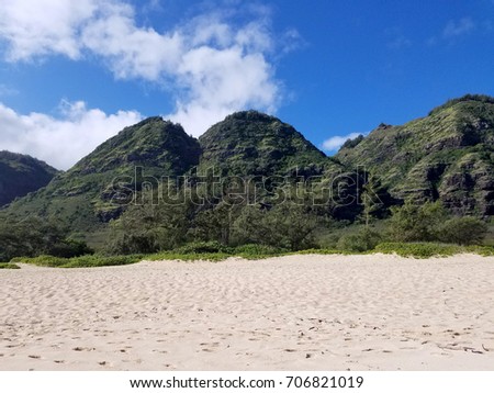 Camp Harold Erdman Beach with lush mountains and Blue sky with clouds.  Camp Harold Erdman Beach  is located on the north shore at the far west end of O'ahu. This is the stretch of sandy beach.