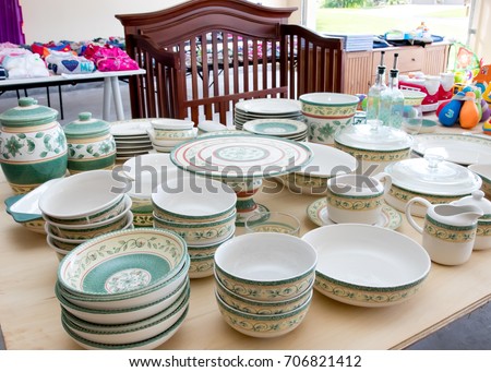 Tables of dishes and baby goods at a suburban garage sale Royalty-Free Stock Photo #706821412