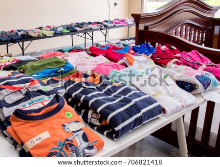 Tables of clothing and baby goods arranged at a suburban garage sale Royalty-Free Stock Photo #706821418