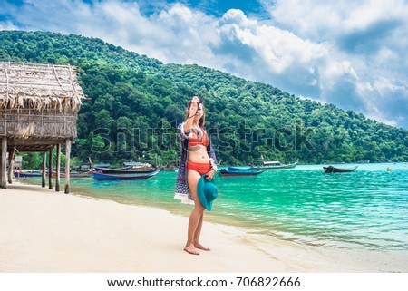 Traveler woman in bikini take photo on sea beach with wooden house and boat background, Morgan village, Andaman sea, Phangnga, Travel in Thailand