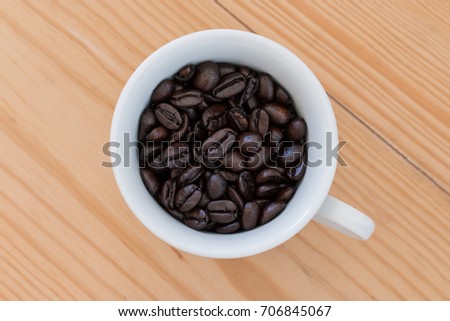 Roasted coffee beans in a cup on old wooden background.