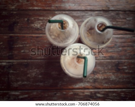Blurry picture.Take away ice coffee in plastic cup put on wooden table in the morning orin break time during work hard all day.