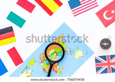 booking trip with map, flags and tourist outfit on white office desk background top view