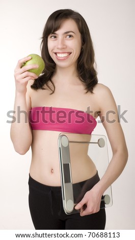 portrait of young smiling girl with green apple and scales