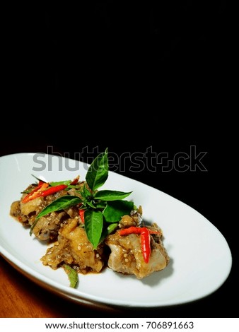 The picture of stir fried spicy pork leg on white dish. black background