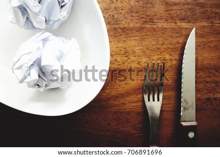 No work No money and No food. The picture of failed work condition consist of disastrously paper on white dish, pencil, fork, spoon, hand and knife above wooden table. selective focus. soft tone style