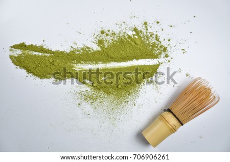 Matcha green tea powder on white background with traditional bamboo tea whisk