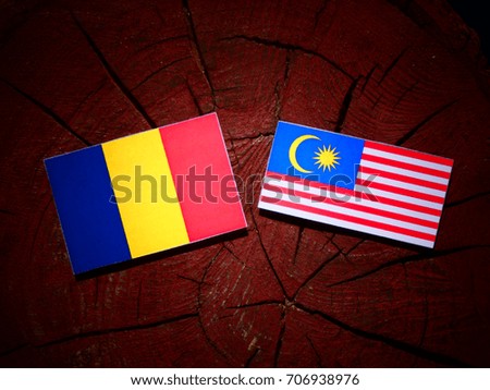 Chad flag with Malaysian flag on a tree stump isolated