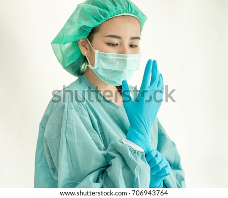 Female surgeon or nurse wearing a sterile suit putting on sterile rubber gloves to perform a surgery, Hand wearing a surgical gloves before starting the operation, Step by step procedures. Royalty-Free Stock Photo #706943764