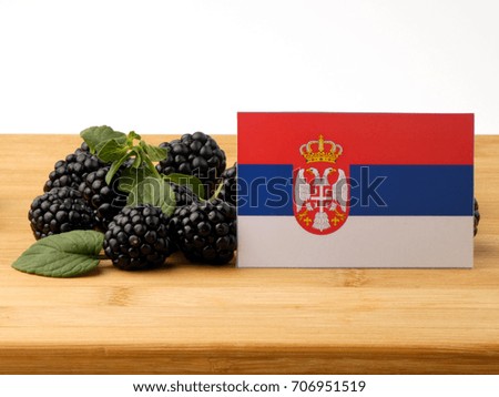 Serbian flag on a wooden panel with blackberries isolated on a white background