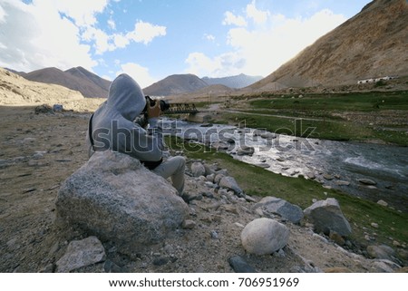 A photographer is taking pictures of farm and wild animals coming to drink water from this river.