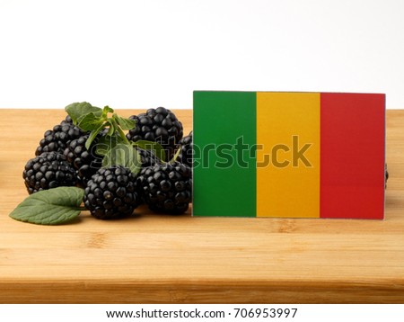 Malian flag on a wooden panel with blackberries isolated on a white background