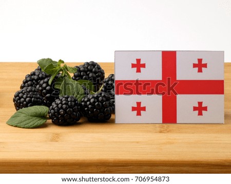 Georgian flag on a wooden panel with blackberries isolated on a white background