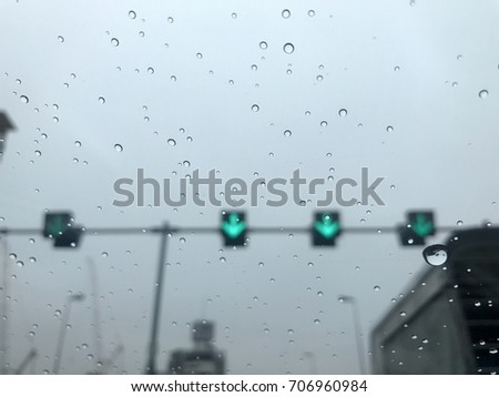 Water drops of rain on glass mirror in the car on the road with green arrow pointing down   and a blur picture abstract background