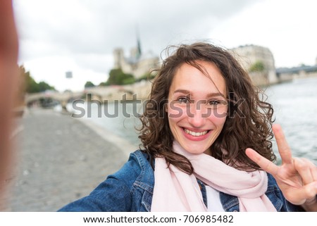 View of a Young woman on holidays in Paris taking selfie in front on Notre Dame - Tourism concept
