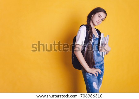 Back to school. Teen girl with books on a bright orange and yellow background. Place for your text.