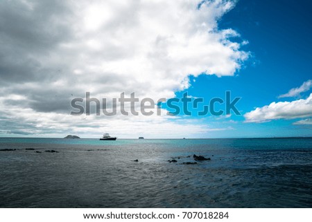 Isolated Tropical Island Beach with Beautiful Sea Waves. Blue Sky, Paradise Nature Background. Luxury Boat Floating on the Beach. Clean Ocean Dynamic Waves. Beach Landscape View. Dramatic Background