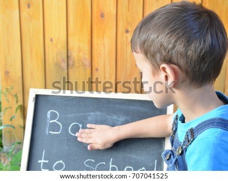 joyful little boy with back board or pack ready for school, write back to school concept