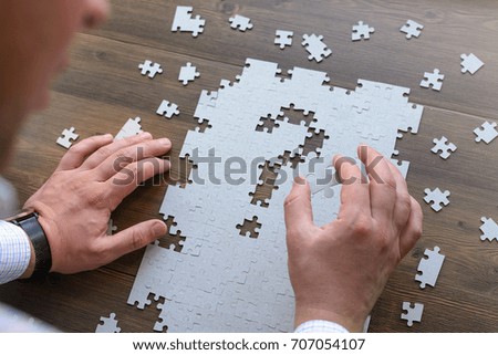 Image of businesswoman connecting elements of white puzzle 