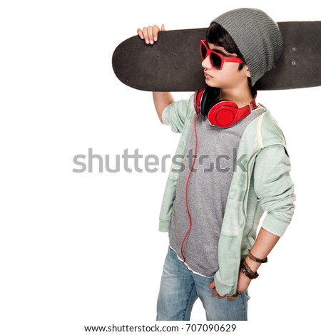 Teen boy with skateboard on the shoulder isolated on white background, stylish guy wearing sunglasses and hat, listening music from earphone, modern life of young people
