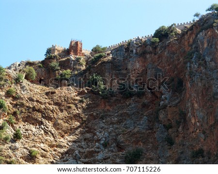 Panoramic picture of high steep cliffs with the ruins of an ancient fortress near the Turkish city of Alanya. View from the sea side