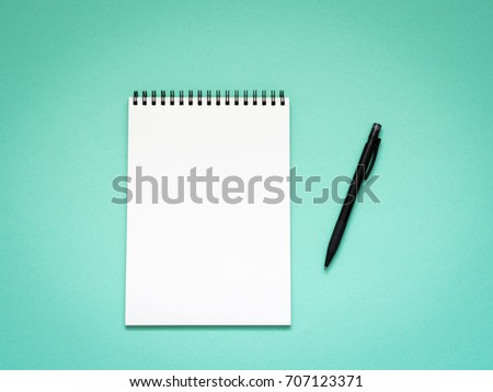 Top view of blank note paper with pen on aqua table background. 