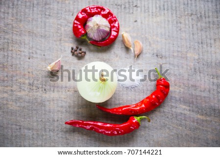 Wooden background with garlic cloves, chili peppers, onion, mix of dry spices and salt.