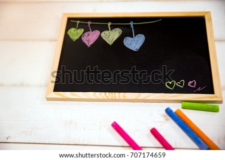 Cartoon heart draw by colorful chalk on wooden blackboard. blackboard and colorful chalk put on white table, 