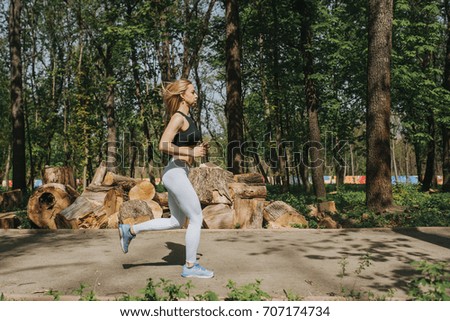 Woman runner running in spring park. Female fitness girl jogging on path in amazing fall foliage landscape nature outside. Beautiful young fitness woman running outdoors.