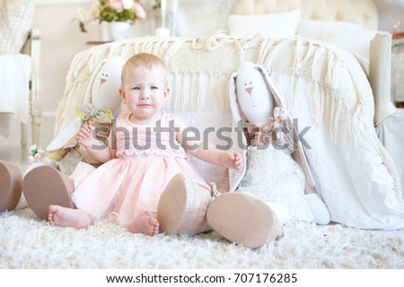photo of little crying girl sitting between toy rabbits 