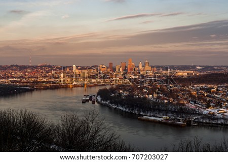A view of the Cincinnati, Ohio skyline and the Ohio River at sunset on a cold winter evening.