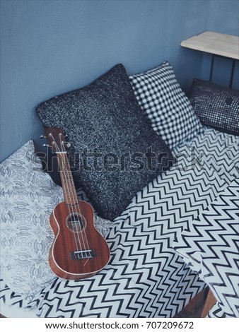 Ukulele on black and white cushions and seat cushion,High-angle shot, summer, Organic,Tropical, Island, music,vacation time.