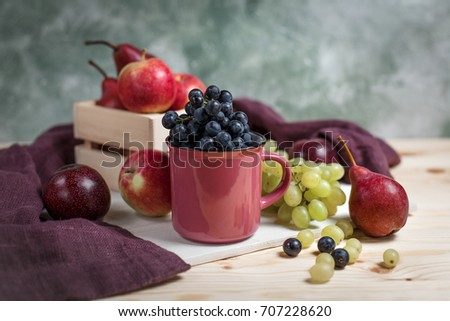 Still life of seasonal fruits in a cup on a wooden table, on a blue background