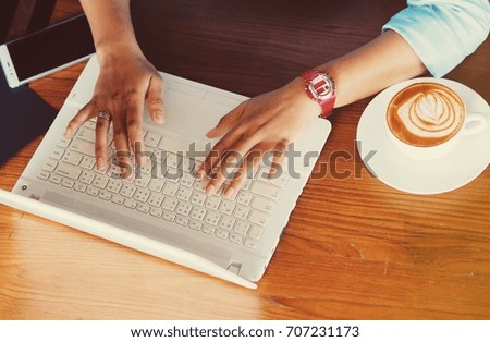 Top view of woman hand using laptop in coffee shop.