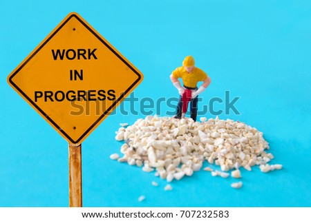 small figure of a man digging concrete street with Work in Progress message.