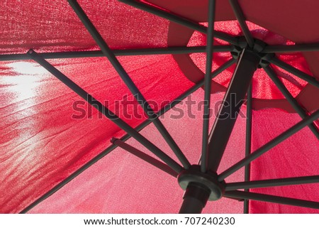 Red parasol with the sun translucent by the canvas
