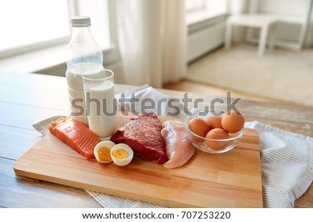 natural food, healthy eating and protein diet concept - raw meat fillet, fish, milk and eggs on wooden table Royalty-Free Stock Photo #707253220